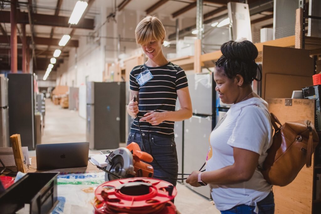 A Tool Library volunteer and member discussing a circular saw.